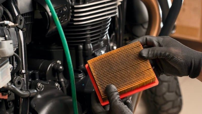 Mechanic Holding Dirty Motorcycle Air Filter in Hand