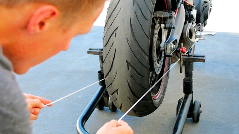 Man checking wheel alignment on motorcycle